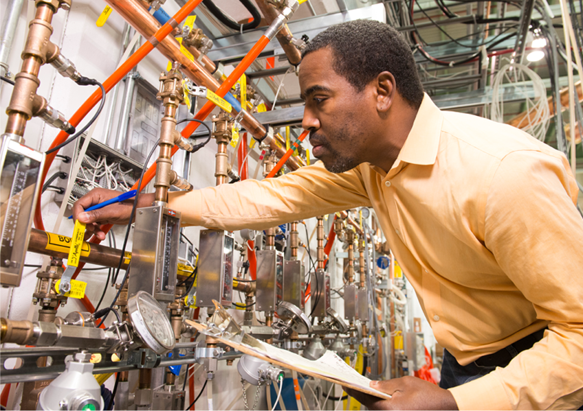 A scientist is examining valves and instruments in a laboratory facility